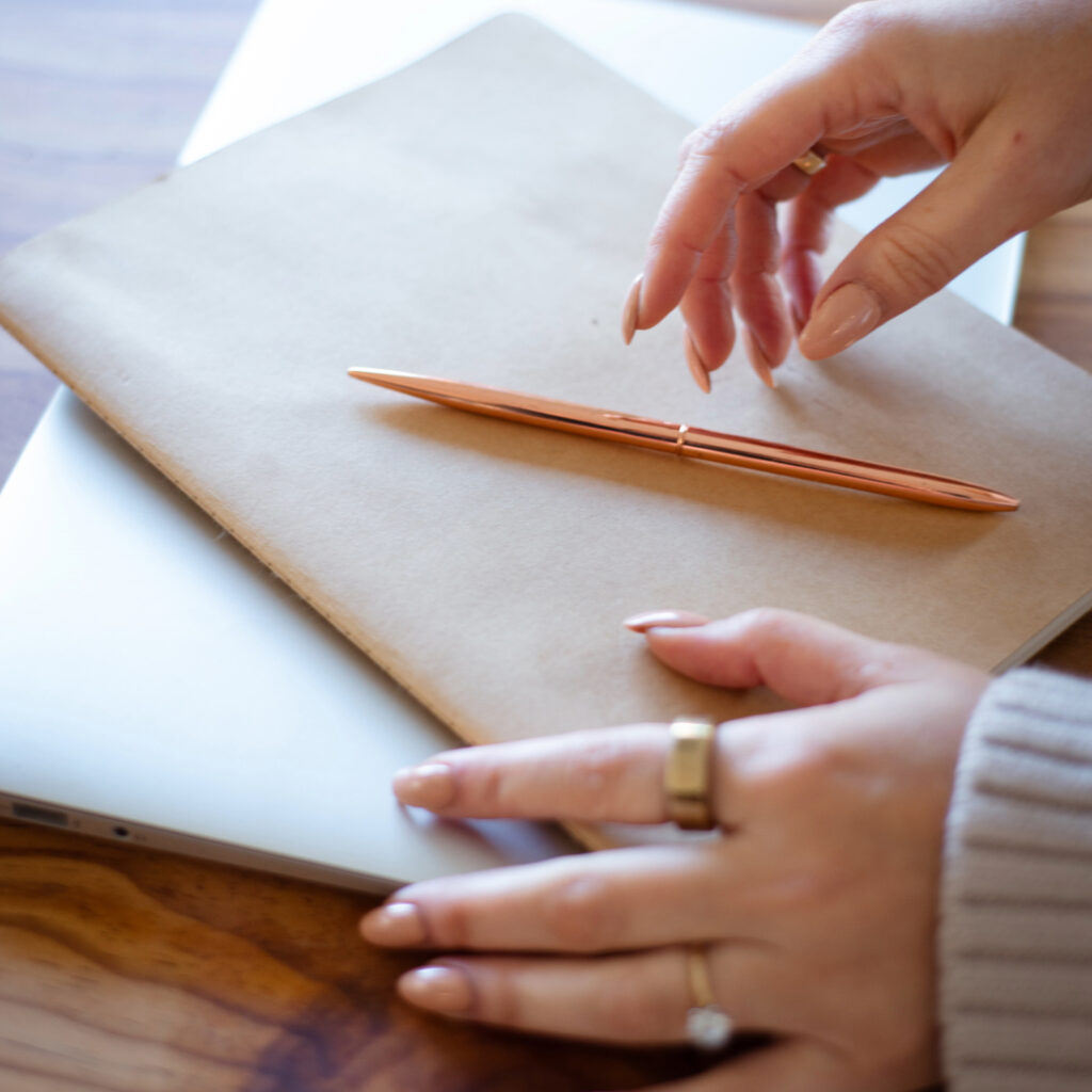 a woman's hands rest over a journal